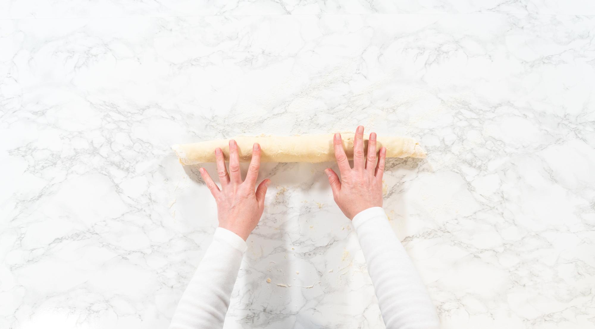 hands preparing dough on marble surface
